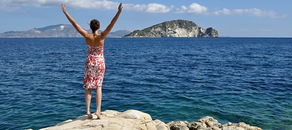 woman with hands up on the coast
